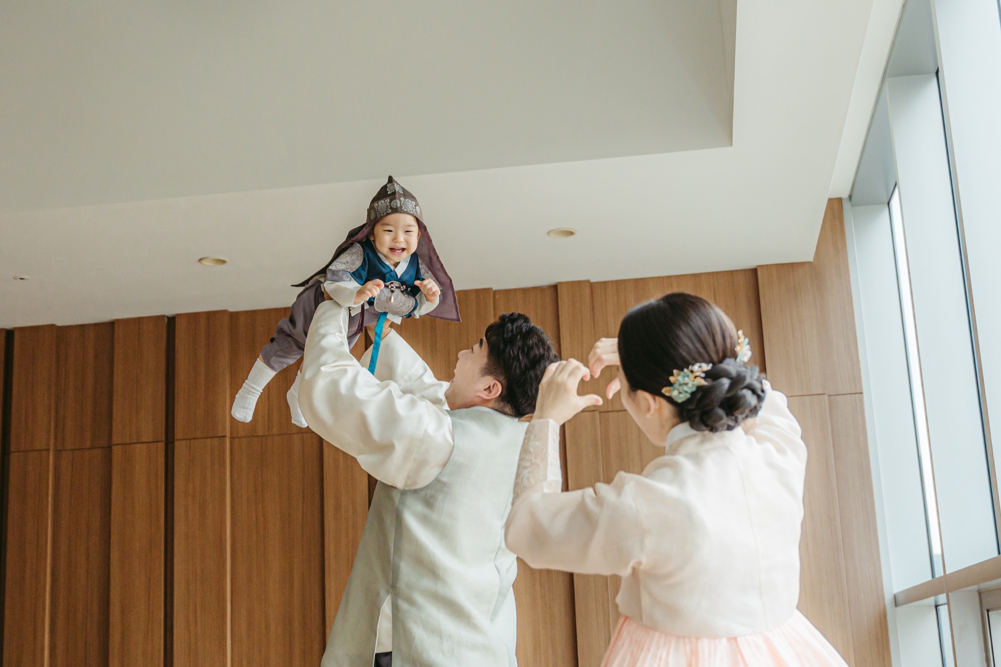아기를 들어 올리며 웃는 엄마 아빠