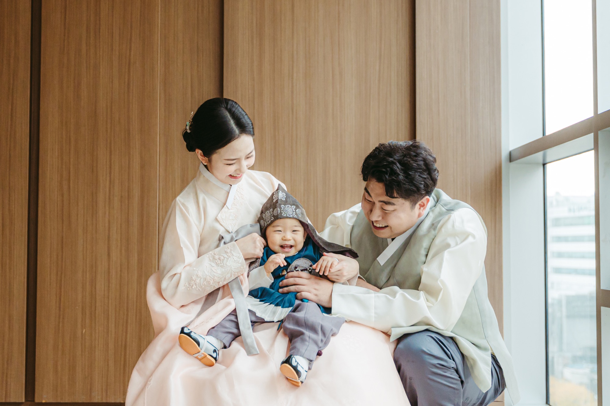 더아너스에서 한복을 입은 아기와 함께 웃는 엄마 아빠
