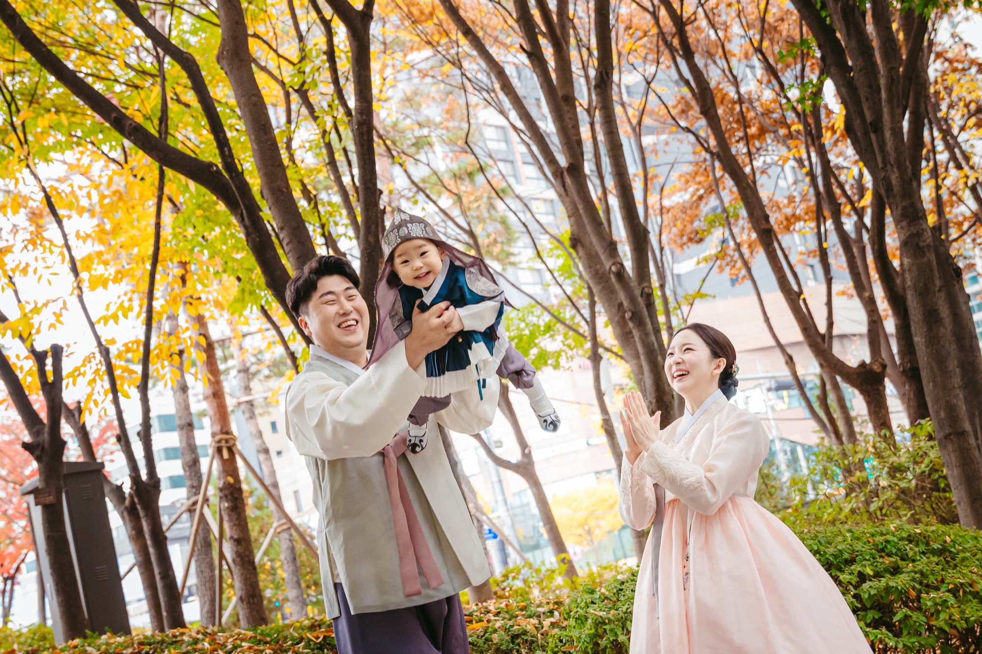 가을 나무 아래 아기를 안고 웃는 가족