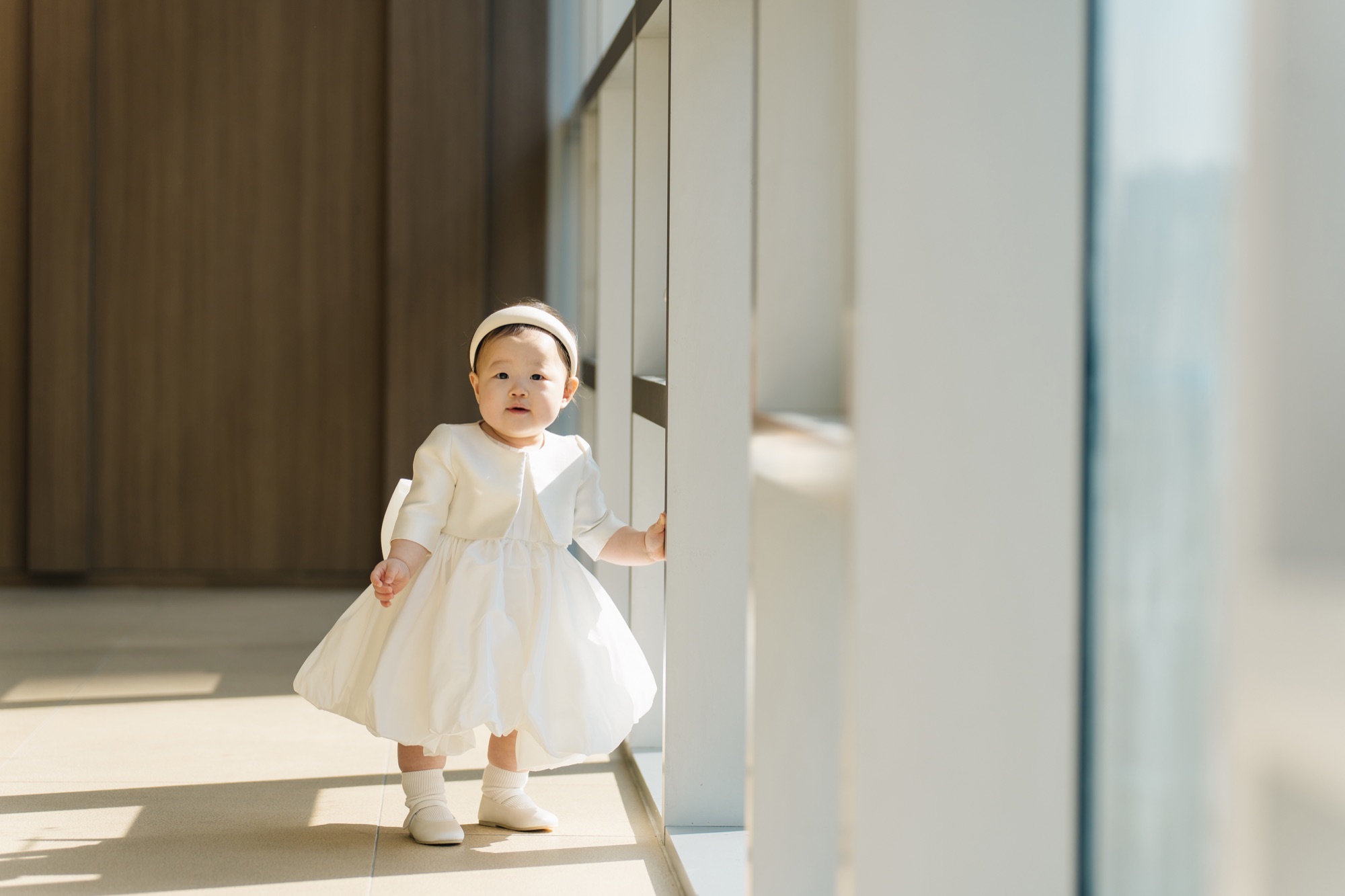창가의 햇살 속에 서 있는 아기