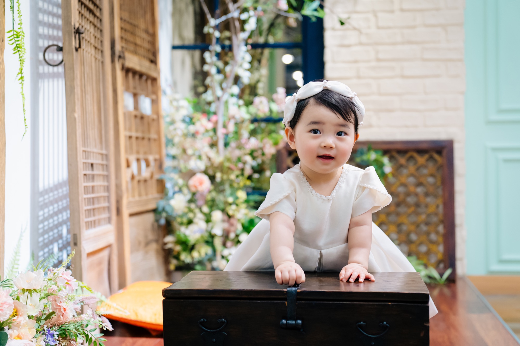 꽃 장식 앞에서 정면을 바라보는 아기